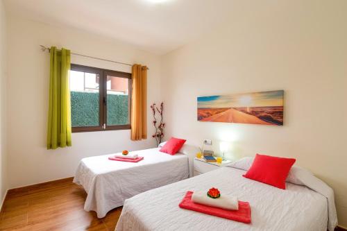 pokój z 2 łóżkami i czerwonymi ręcznikami w obiekcie Villa Fakay by Villa Plus w mieście Caleta De Fuste