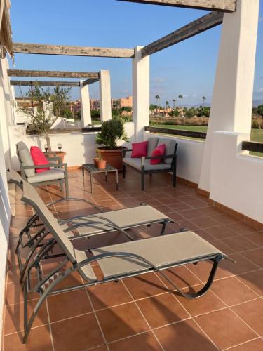 un patio con sillas y mesas en un balcón en Penthouse Mar Menor Golf Resort - Stylish, Bright en Torre-Pacheco