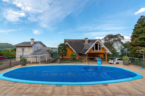 una gran piscina azul frente a una casa en Rosa Casa Várzea Grande, en Gramado