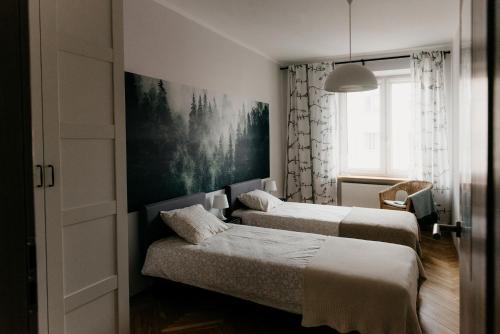 a bedroom with two beds and a painting on the wall at Flathouse Apartment Centrum in Białystok