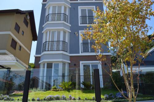 un edificio blanco alto con un árbol delante de él en Rosa Edifício Van Gogh, en Gramado