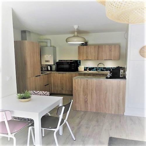 a kitchen with a white table and chairs in a room at Azurea - Charmant appartement à Andernos-les-Bains in Andernos-les-Bains