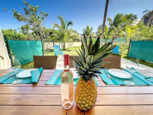 a wooden table with a bottle of wine and a pineapple at Villa Carpe Diem sea front pool Orient Bay in Orient Bay