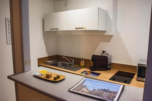 eine Küche mit einer Spüle und einer Theke mit einem Buch in der Unterkunft Yellow Studio - Poitiers Coeur de ville in Poitiers