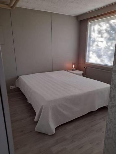 a bedroom with a large white bed and a window at Huoneisto noin 55m2 perusvarustein. in Knivsund