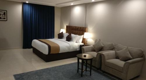 a bedroom with a bed and a couch and a chair at Yan Apartments in Jeddah
