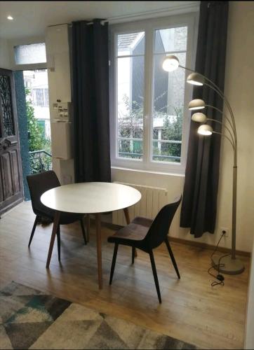 une salle à manger avec une table, des chaises et une lampe dans l'établissement Villa des Roses - Appart T2, 32m2, RDC, vue sur jardin, 