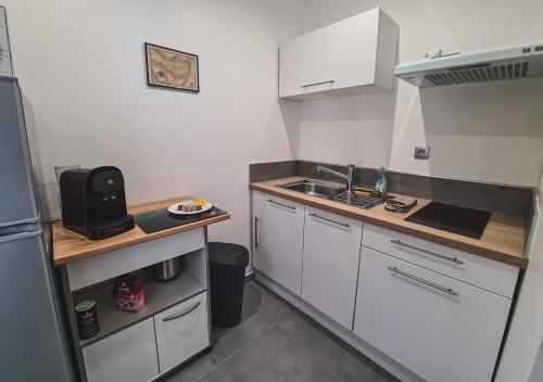 a small kitchen with white cabinets and a sink at Appart Saint Cyprien + Parking privatif in Poitiers