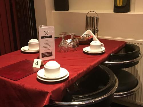 a red table with black chairs and white dishes on it at Belmont Hotel in Blackpool