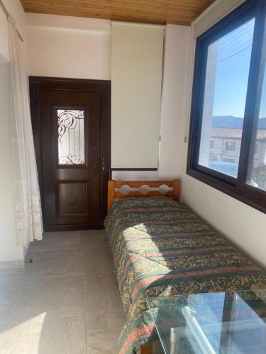 sypialnia z łóżkiem, oknem i drzwiami w obiekcie TheonikosHouse w mieście Agros