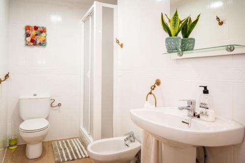 a white bathroom with a toilet and a sink at Casa rural la balsa in Anna