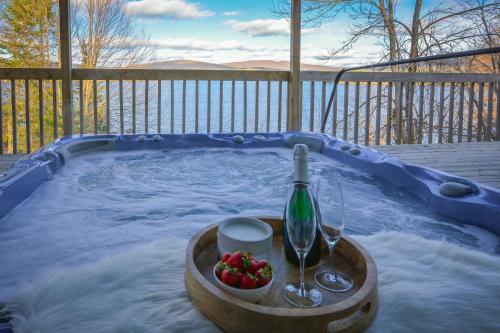 a hot tub with a bottle of wine and two glasses at Chalet Le Pélican in Lac-Superieur
