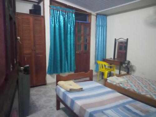a bedroom with two beds and a table and a chair at Casa de los Cruz in Leticia