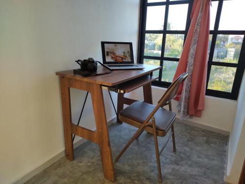 a wooden desk with a laptop on it with a chair at Casa Calandria in Chicxulub