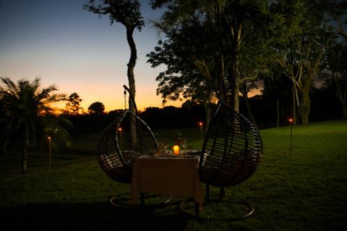 a table and chairs with a candle in a field at Sanma Hotel in Foz do Iguaçu