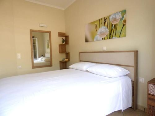 a bedroom with a white bed and a mirror at Agios Leon Apartment 2 in Agios Leon