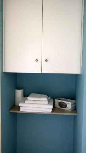 a shelf with white cabinets and towels on a blue wall at Agios Leon Apartment 2 in Agios Leon