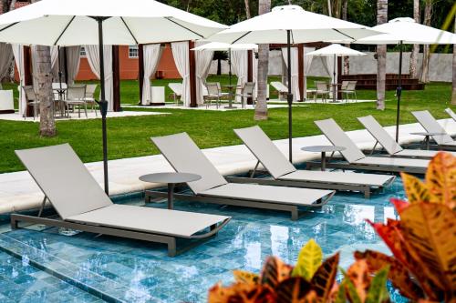 a row of lounge chairs and umbrellas on a pool at Sanma Hotel in Foz do Iguaçu