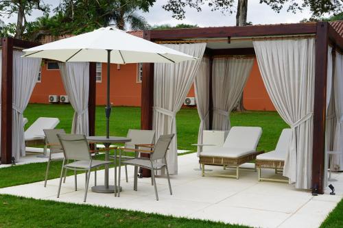 a patio with a table and chairs and an umbrella at Sanma Hotel in Foz do Iguaçu