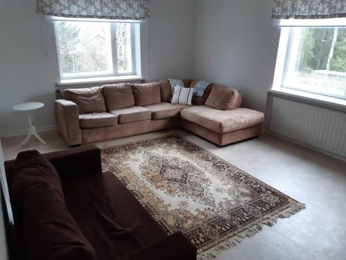 een woonkamer met een bruine bank en een tapijt bij Willa Witsari 65m2 asunto in Kokkola