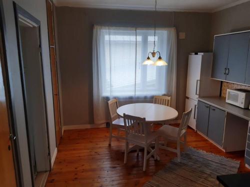 een keuken met een tafel en stoelen en een keuken met een koelkast bij Willa Witsari 65m2 asunto in Kokkola