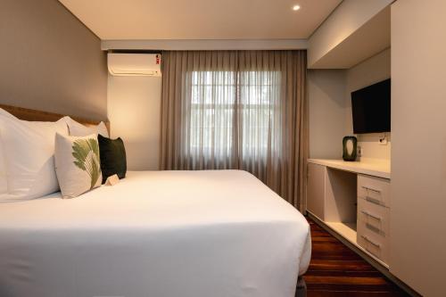 a hotel room with a large white bed and a window at Sanma Hotel in Foz do Iguaçu
