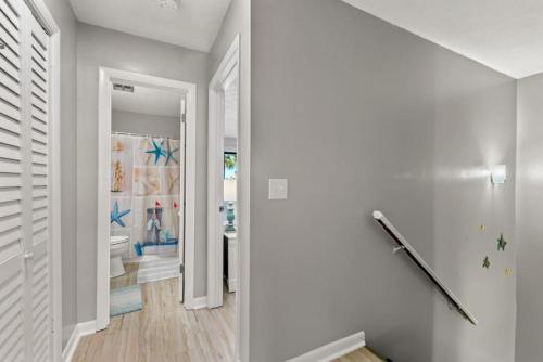 a hallway with white walls and a hallway with a bathroom at Beach Haven - Seasonal Hot Tub, Fire Pit, BBQ, 700 Feet to Beach, Central PCB, FREE Daily Activities, & More! in Panama City Beach