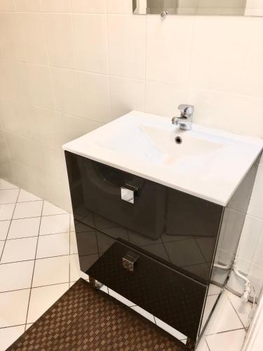 La salle de bains est pourvue d'un lavabo blanc et d'une armoire noire. dans l'établissement Studio Apartment near to Paris, à Créteil