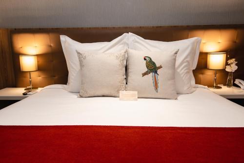 a bed with white pillows with a bird on it at Sanma Hotel in Foz do Iguaçu
