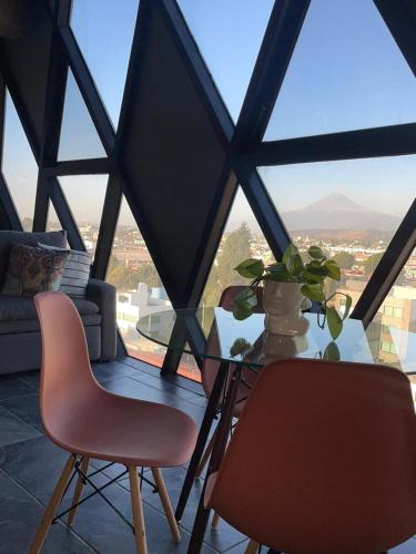 a glass table with two chairs and a table with a window at Loft industrial vista a los volcanes in Cholula