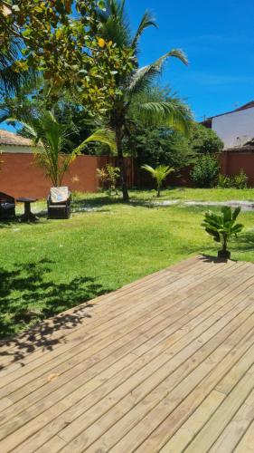 une terrasse en bois dans une cour avec des arbres et de l'herbe dans l'établissement Cantinho Braslis Suíte linda e aconchegante em Caraiva, há 10 minutos da praia, à Porto Seguro