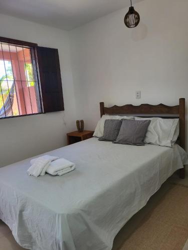 1 dormitorio con 1 cama grande y 2 toallas. en Cantinho Braslis Suíte linda e aconchegante em Caraiva, há 10 minutos da praia, en Porto Seguro