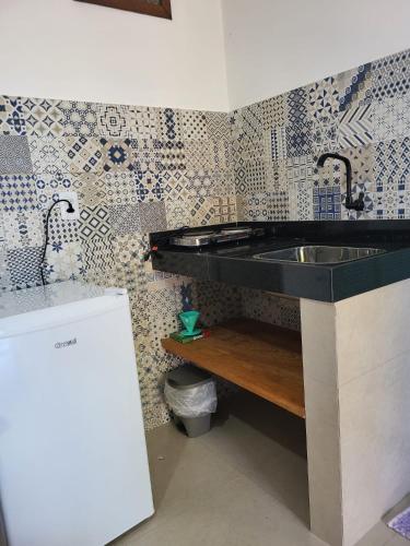 una cocina con fregadero y una pared con azulejos en Cantinho Braslis Suíte linda e aconchegante em Caraiva, há 10 minutos da praia, en Porto Seguro