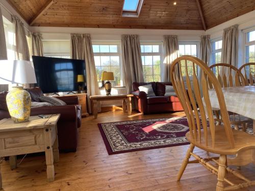 een woonkamer met een bank en een tafel en stoelen bij Lake Big, Five Bedroom Holiday Home Rosslare Strand, County Wexford in Mervyn