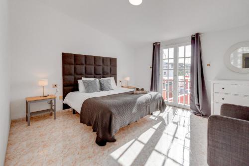 um quarto branco com uma cama grande e uma janela em Bonita Casa Nina con Jacuzzi By Paramount Holidays em Playa de San Juan