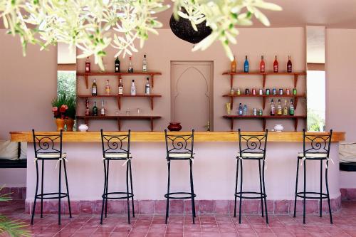 a bar with four stools in front of a counter at La Maison Des Oliviers in Marrakesh
