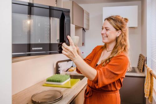 a woman standing in a kitchen using a microwave at Viktoria Guesthouse in Westerlo