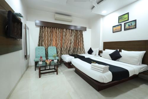 a bedroom with a large bed and two blue chairs at Saish Hotel Shirdi in Shirdi