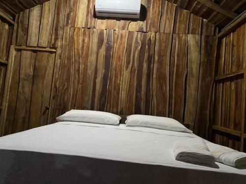 a bed in a room with a wooden wall at Finca Avellanas in Playa Avellana