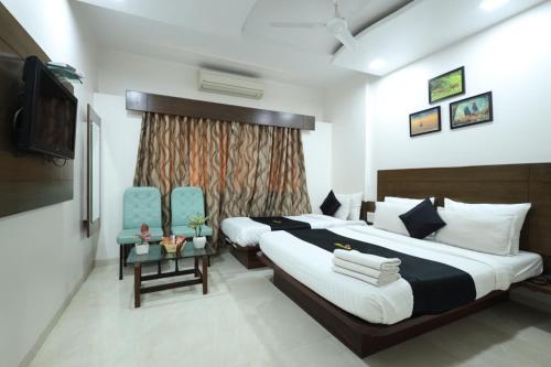 a bedroom with a large bed and two blue chairs at Saish Hotel Shirdi in Shirdi