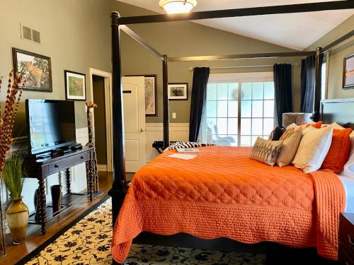 1 dormitorio con 1 cama de color naranja y TV en Explorer House Bed & Breakfast en Niagara on the Lake