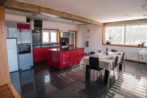 a kitchen with red cabinets and a table with chairs at Casa do Lagar in Geres