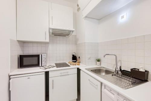 a white kitchen with a sink and a microwave at Le Cosy - Free Parking - 2 min métro - 5 min Paris in Charenton-le-Pont