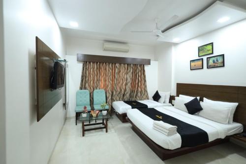 a hotel room with a bed and a television at Saish Hotel Shirdi in Shirdi