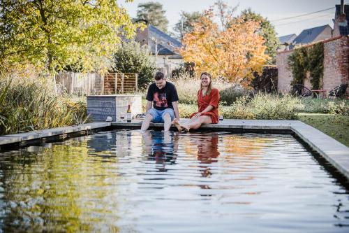 a man and woman sitting on the edge of a pool of water at Viktoria Guesthouse in Westerlo