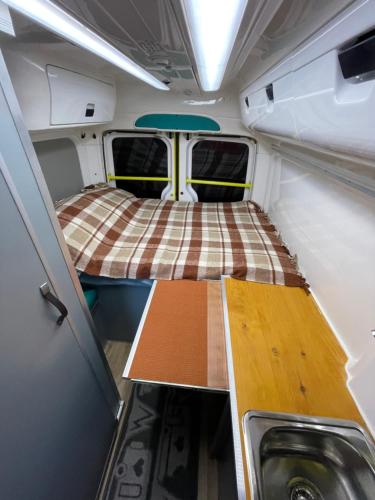 um pequeno quarto com uma cama e uma mesa num trailer em Autocaravana em Puerto de Sagunto