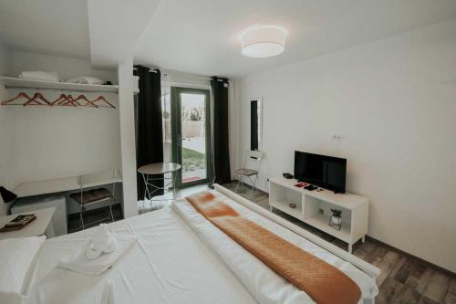 a white bedroom with a large bed and a tv at Pensiunea Delta Drill in Sfântu Gheorghe