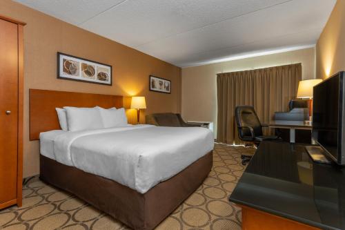 a hotel room with a bed and a desk and a television at Comfort Inn Amherst in Amherst