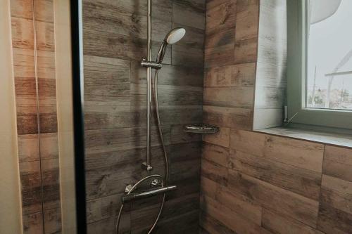 y baño con ducha y pared de madera. en Pensiunea Delta Drill en Sfântu Gheorghe