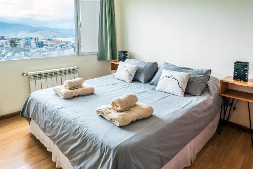 uma cama com toalhas com uma grande janela em Belgrano R em Ushuaia